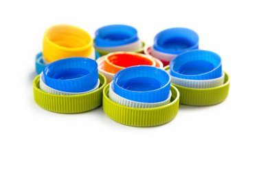 Beyaz arkaplandaki plastik kapsüllerin bileşimi. Geri dönüşümlü plastik şişe kapaklarının üst görüntüsü. Ayrı çöp toplama yeri. Protez için plastik geri dönüşümü. Seçici odak. 