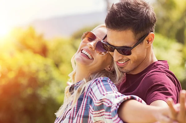Seven çift Park'ta güneşin tadını genç. Neşeli erkek ve güzel kız arkadaşı açık güneş gözlüğü takıyor. Adam ang kız aşık açık elele outstretchetd silah.