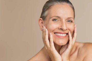 Olgun kadın yüz el ile gülümseyen güzellik portresi. Anti-aging tedavi sonrası kendini mutlu kadın kıdemli portre yüzü. Gülümseyen güzellik kameraya mükemmel cildi dokunmadan süre seyir.