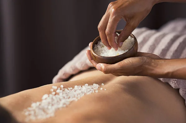 女性のビューティー サロンでマッサージをしているマッサージ師の手 美容セラピスト塩を注ぐ女性健康スパでスクラブします ごしごし洗うと肌ケアのコンセプト — ストック写真