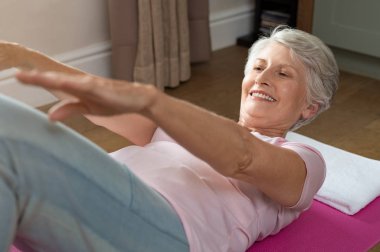 Sağlıklı kadın kıdemli mide egzersizi evde yapıyor. Yaşlı kadın egzersiz yoga mat yapmak. Evde karın egzersiz yaparak germe uygun eski Büyükanne.