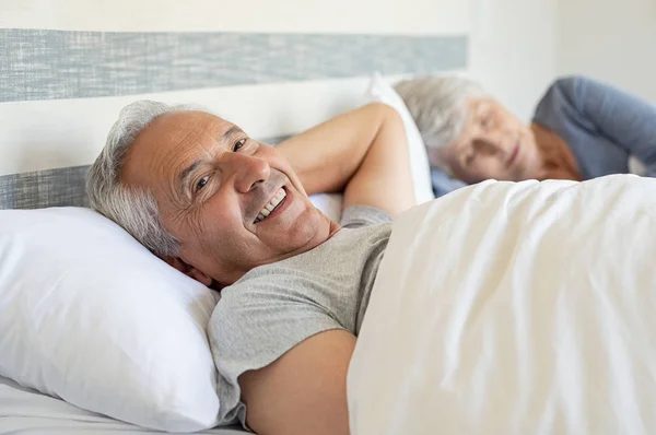 Retrato Anciano Sonriente Acostado Cama Mientras Esposa Dormía Fondo Pareja —  Fotos de Stock