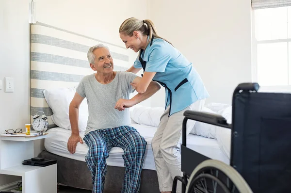 Uśmiechający Się Pielęgniarka Pomoc Starszy Człowiek Aby Wstać Łóżka Opieka — Zdjęcie stockowe
