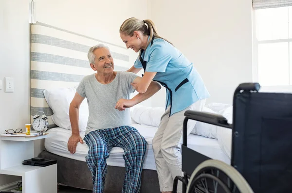 Lachende Verpleegkundige Bijstaan Van Senior Man Opstaan Uit Bed Zorg — Stockfoto