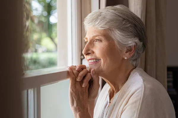 Щаслива Старша Жінка Стоїть Вікні Дивиться Вулицю Красива Бабуся Посміхається — стокове фото