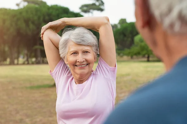 Leende Senior Kvinna Tittar Man Samtidigt Gör Arm Stretching Motion — Stockfoto