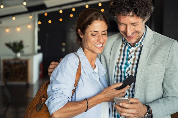Lächelndes Älteres Paar Das Sich Umarmt Während Auf Sein Smartphone — Stockfoto