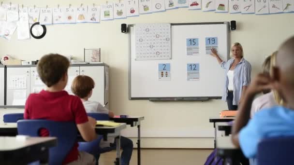 老师在教室里教如何依靠白板 教数学的女小学生坐在课堂上 学校的孩子们在现代教室里学习数学 学校男孩在课上举起胳膊 — 图库视频影像