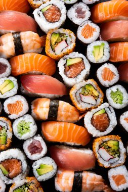 Üstten görünüm suşi yemek çeşitliliği. Yüksek açılı görünüş nigiri, maki, hosomaki, uramaki ve rulo ton balığı, somon, avokado ve karides üst üste. Çiğ balık ve pirinç ile geleneksel Japon yemekleri.