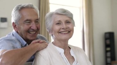 Mutlu sağlıklı üst düzey çift evde portresi. Kameraya ararken romantik eski çift oturma kanepede birlikte. Neşeli yaşlı karı ve koca emekli olduktan sonra hayatın tadını.