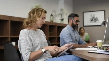 Olgun işkadını dijital tablet iş toplantı sırasında kullanma. Postaları kontrol ve kameraya bakarken tablet yanıtlarken iş kadını ortalarında başarılı. Ofis Toplantı b meslektaşları ile çalışan güzel gülümseyen casual Bayan portresi