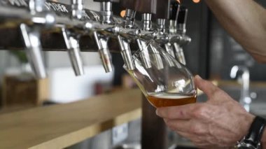 Barmen büyük lager bira dokunun içinde dökme el. Bira musluk kullanarak cam içinde hizmet veren el closeup. Barmen el dökülen sarı bir fıçı bira barda bira musluk, yakın çekim.