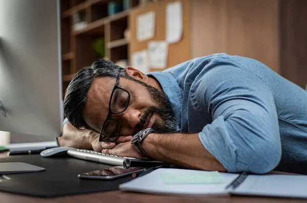 疲れた民族ビジネスマンがオフィスで眠っています 中東のビジネスの男性眼鏡と遅くまで働いた コンピューターのキーボードで眠ってしまった 彼の職場に眠っている創造的なカジュアルな男 — ストック写真