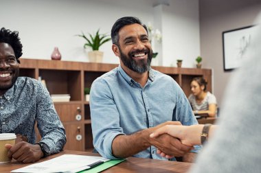 Toplantı Salonu otururken el sıkışan iki iş adamları. Orta Doğu işadamı işkadını el salla. Kapalı bir el sıkışma ile anlaşma imzalama mutlu gülümseyen latin adam portresi.