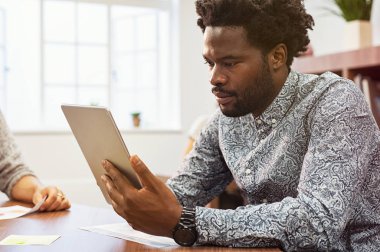 Afrika kökenli Amerikalı girişimci dijital tablet onun stüdyosunda kullanma. Yaratıcı ajansı dijital tablet üzerinde çalışan işadamı yoğunlaşmıştır. Siyah casual adam ofis masa başında oturan dizüstü bilgisayarda e-posta kontrol.