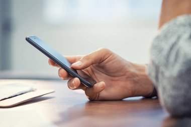 Ahşap masa üzerinde akıllı telefon kullanan kadın portre el. Akıllı telefon kısa mesaj yazarak işkadını. Casual Bayan el cep telefonu boş ekran ile ofiste tutarak.