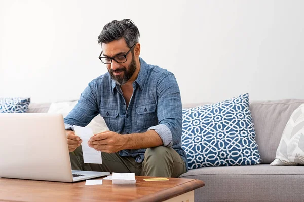 Mature Casual Man Using Laptop While Looking Invoice Smiling Latin — Stock Photo, Image