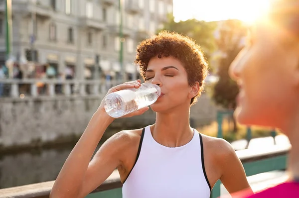 Mujer atlética bebiendo agua después del entrenamiento — Foto de Stock