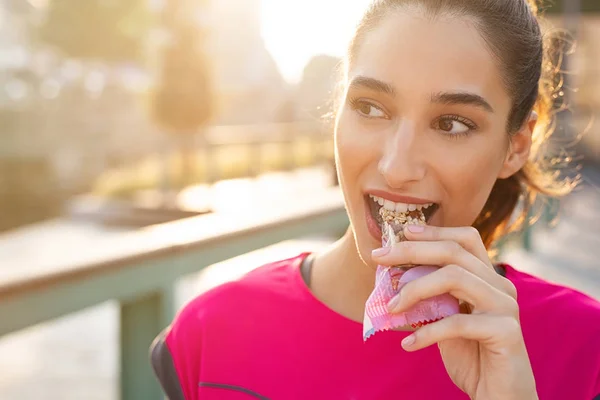 Sportliche Frau isst Energieriegel — Stockfoto