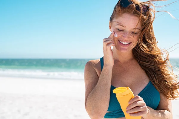 Frau mit Sommersprossen trägt Sonnencreme auf Gesicht auf — Stockfoto