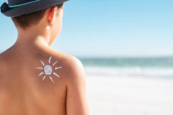 Zonnebrandcrème op de schouder van de jongen — Stockfoto