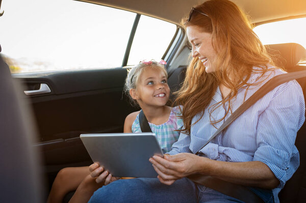 Mother and daughter using digital tablet in car