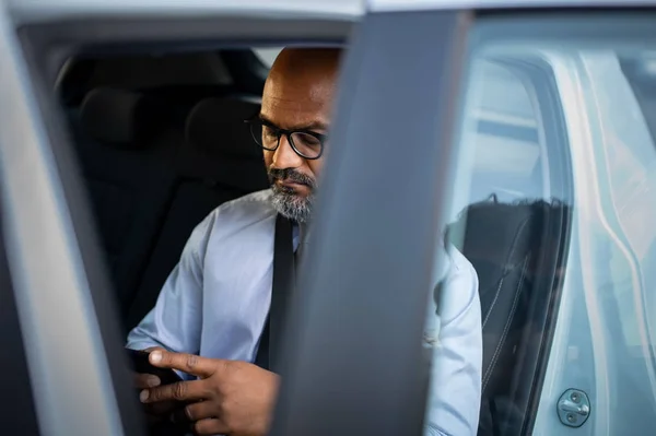 Mature african businessman using smartphone in car — Stock Photo, Image