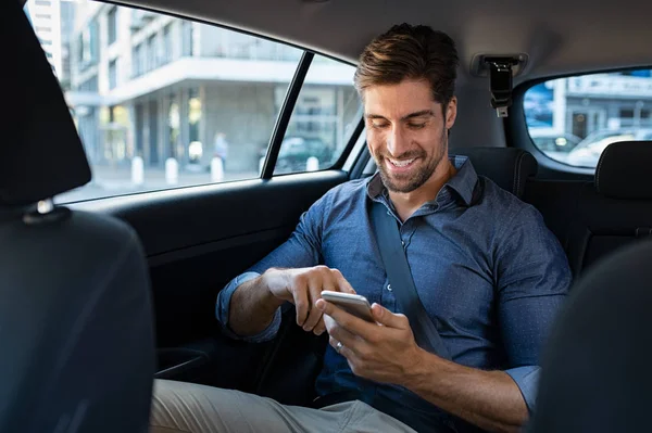 Glad affärsman i bilen med telefonen — Stockfoto