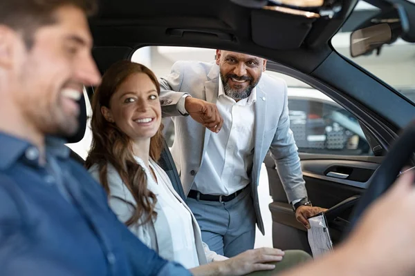 Salesman showing new car to couple — Stock Photo, Image