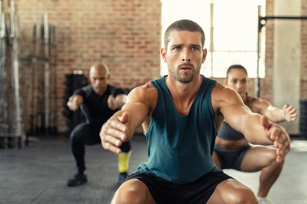 Hombre de fitness en cuclillas con clase en el gimnasio —  Fotos de Stock