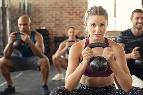 Mujer de fitness en cuclillas con campana hervidor de agua —  Fotos de Stock