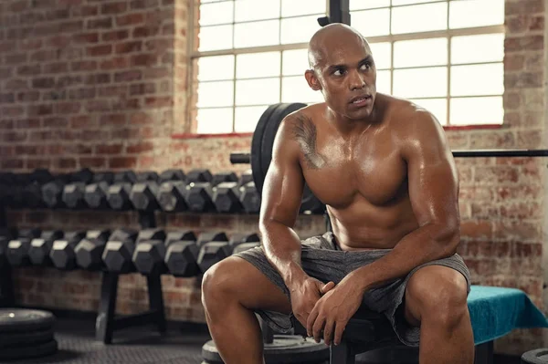 Muscular sweaty man resting in gym