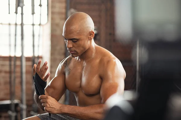 Shirtless muscular man wearing gloves at gym