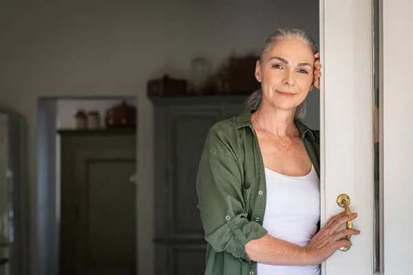 Olgun kadın kapıda duruyor — Stok fotoğraf