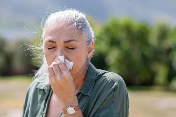 Mujer mayor que sopla la nariz en servilleta — Foto de Stock