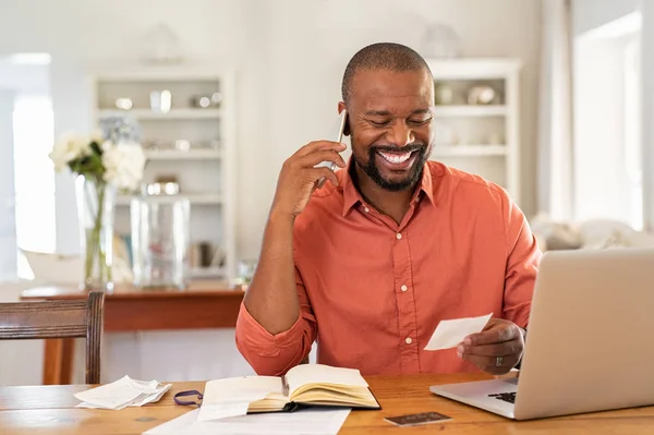 Homem feliz lendo fatura e falando ao telefone — Fotografia de Stock