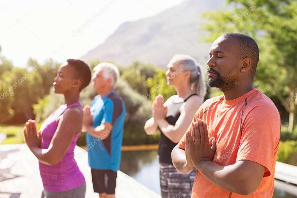 Mature people meditating together at park