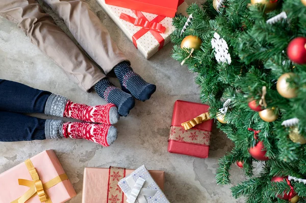 Ζευγάρι σε χειμερινές κάλτσες ξαπλωμένο επόμενο χριστουγεννιάτικο δέντρο — Φωτογραφία Αρχείου