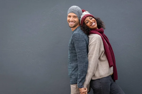 Счастливая пара в зимней одежде прислонилась к спине — стоковое фото