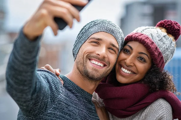 Sorrindo casal multiétnico tomando selfie no inverno — Fotografia de Stock