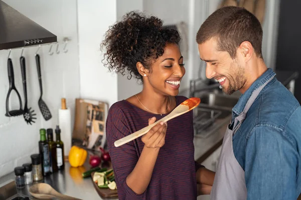 Pareja multiétnica degustación de alimentos de cuchara de madera —  Fotos de Stock