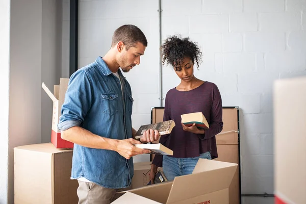 Young couple unpacking books from cardboard boxes — Stock Photo, Image