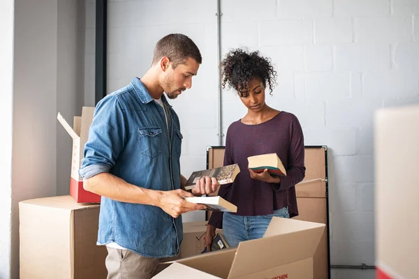 Pareja joven desempacando libros de cajas de cartón — Foto de Stock