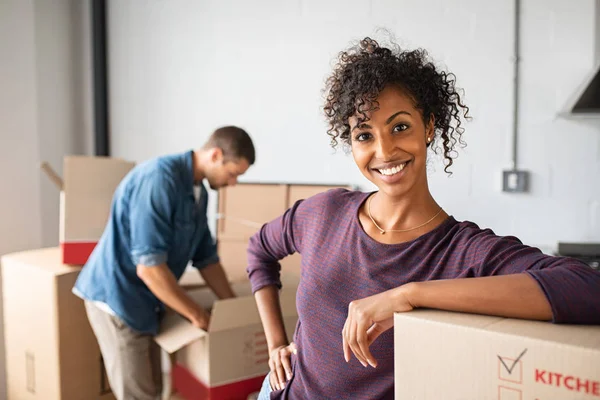 Woman leaning on cardboard box while moving house — Stock Photo, Image