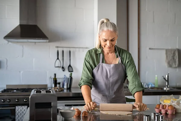 Donna anziana rotolamento pasta biscotto a casa — Foto Stock