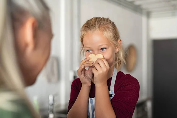 Menina segurando biscoito com rosto engraçado — Fotografia de Stock