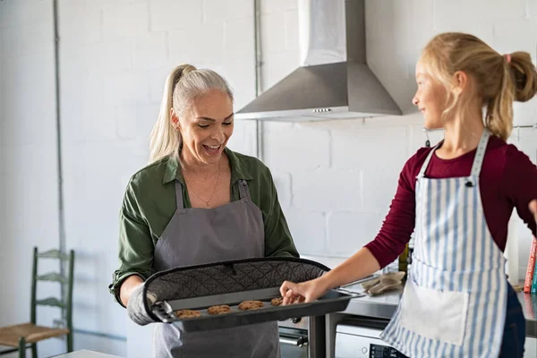 Ragazza che prende biscotti caldi da bakeware — Foto Stock