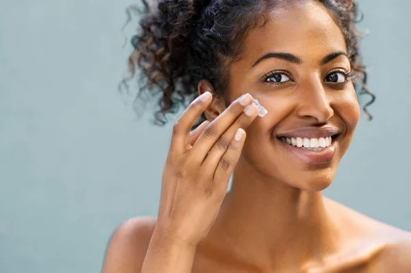 Vrouw vochtinbrengende crème toe te passen op gezicht — Stockfoto