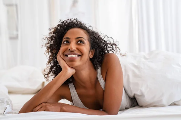 Happy black woman in bed thinking — Stock Photo, Image