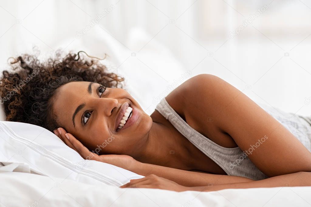 Young black woman laughing in bed